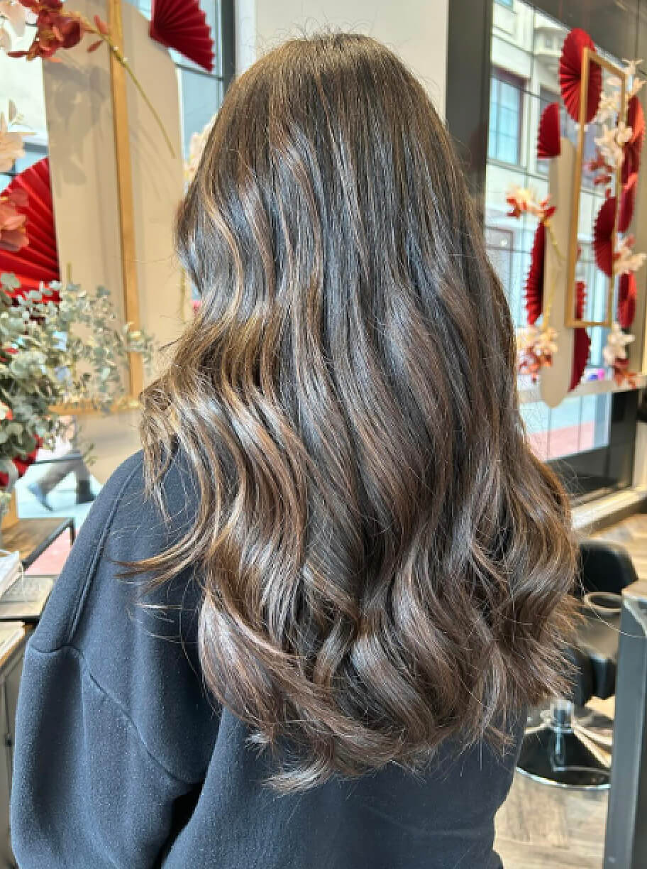 Imagen de galería de corte de pelo largo con ondas de mujer con color moreno