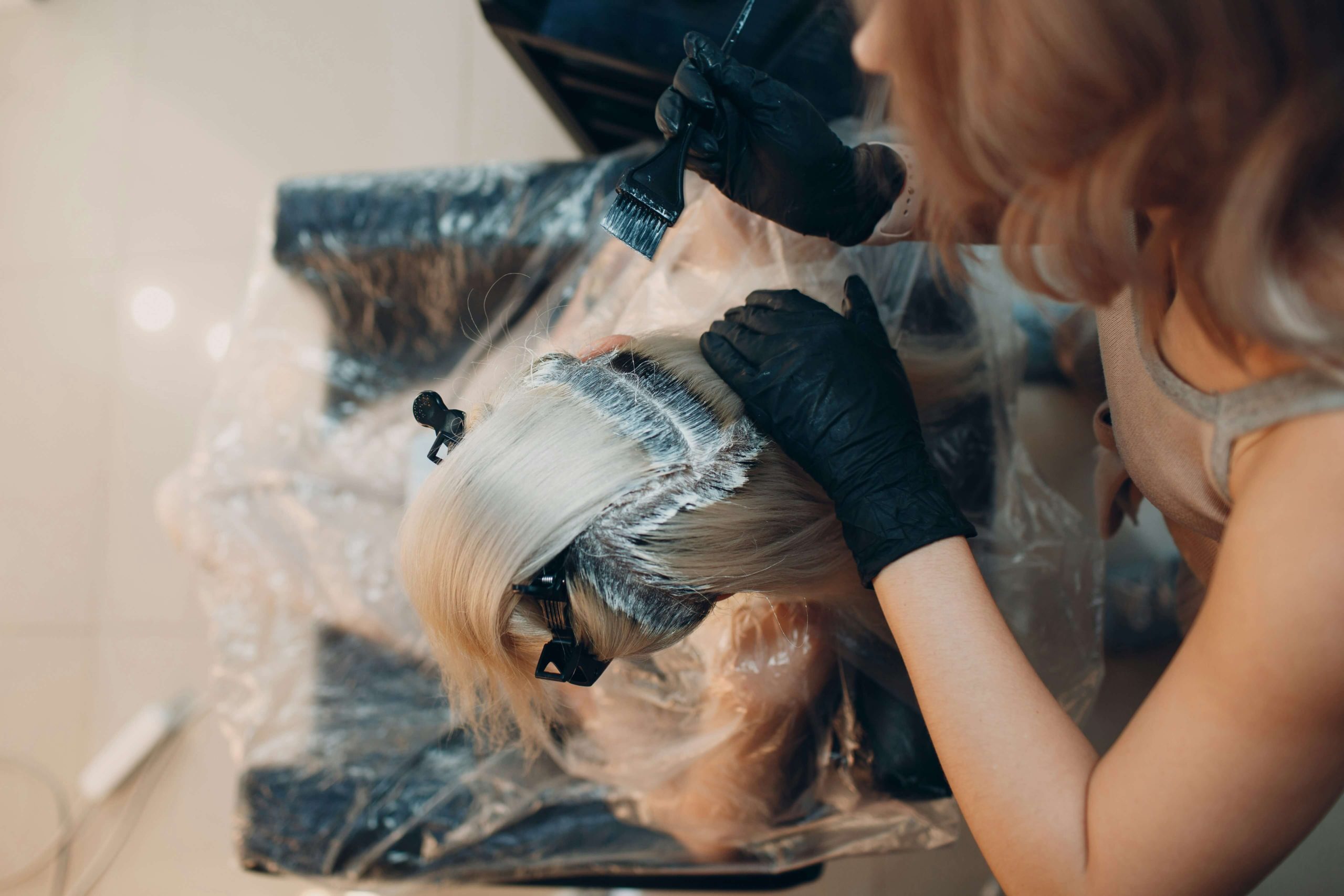 Imagen de una mujer aplicando tinte a otra para cambiar el color del pelo